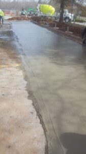 Wide view of new concrete lane poured beside existing parking lot