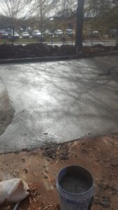 Freshly finished concrete apron with control joints beside new curb