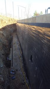 Poured concrete wall with drainage membrane before trench backfill