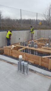 Concrete retaining wall and conduit-filled pad forms ready for pour