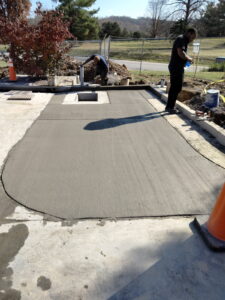 A broom-finished concrete pad with curb and drainage opening, poured for a commercial site.