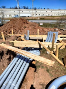 Underground conduit run staged to a formed concrete pad.