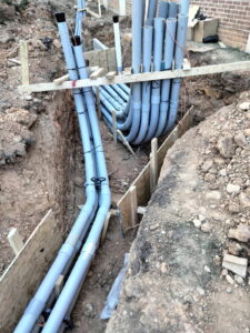 Conduit stub-ups braced in position along a building wall.