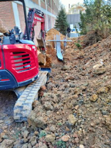 Trenching for new underground conduit at an institutional building.