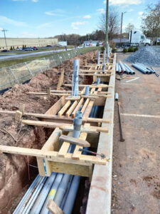 Forming a concrete-encased conduit run along a commercial parking area.