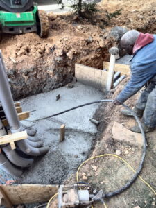 Placing and vibrating concrete around the conduit to encase it.