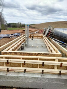 Wall forms set on the base slab with conduit sleeves in place.